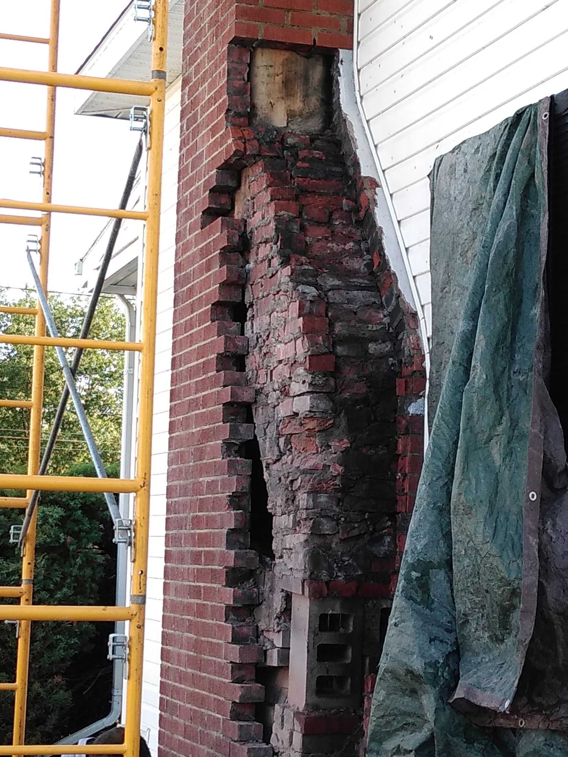A yellow scaffolding is next to a brick wall