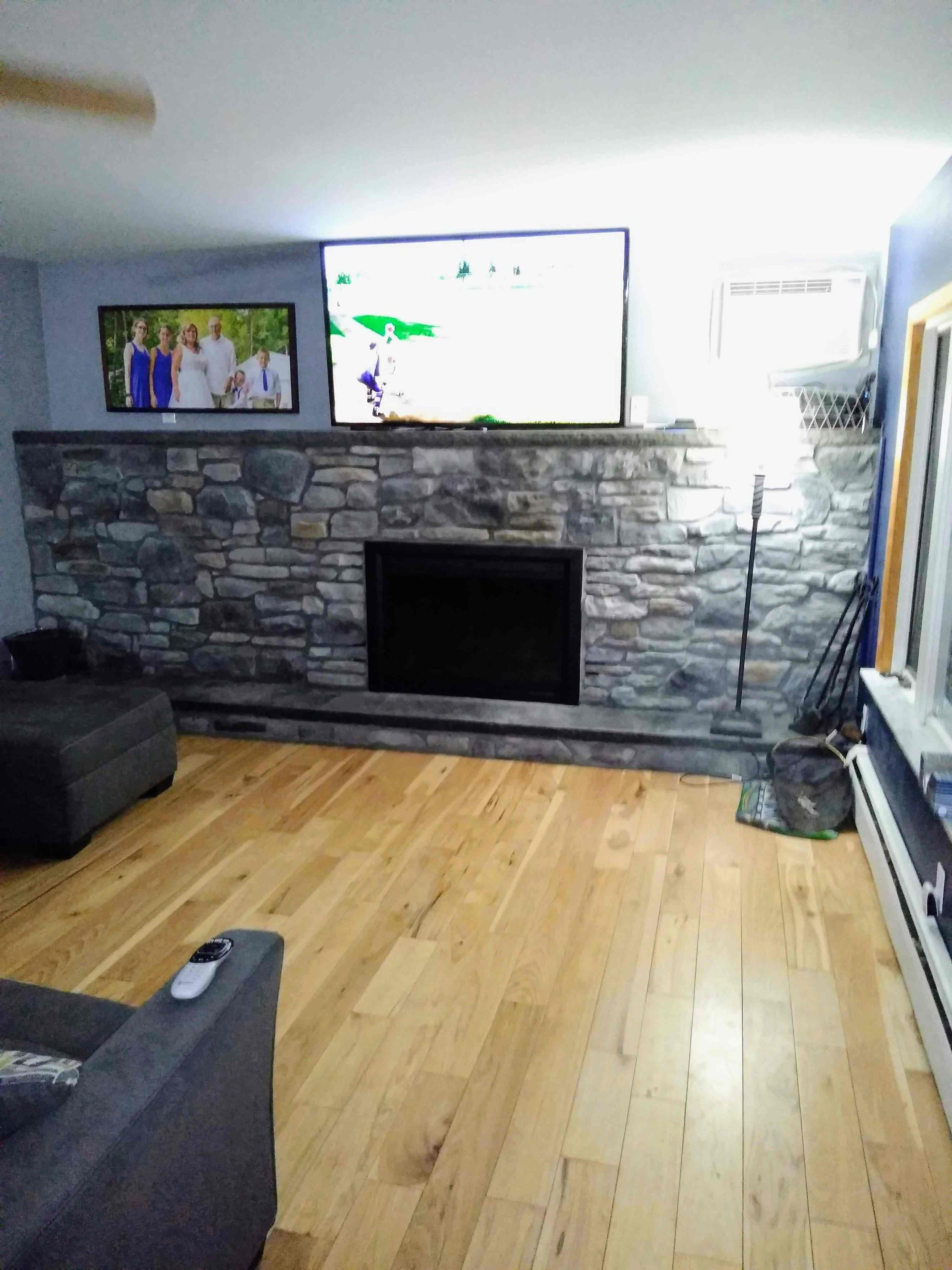 A living room with a stone fireplace and a flat screen tv