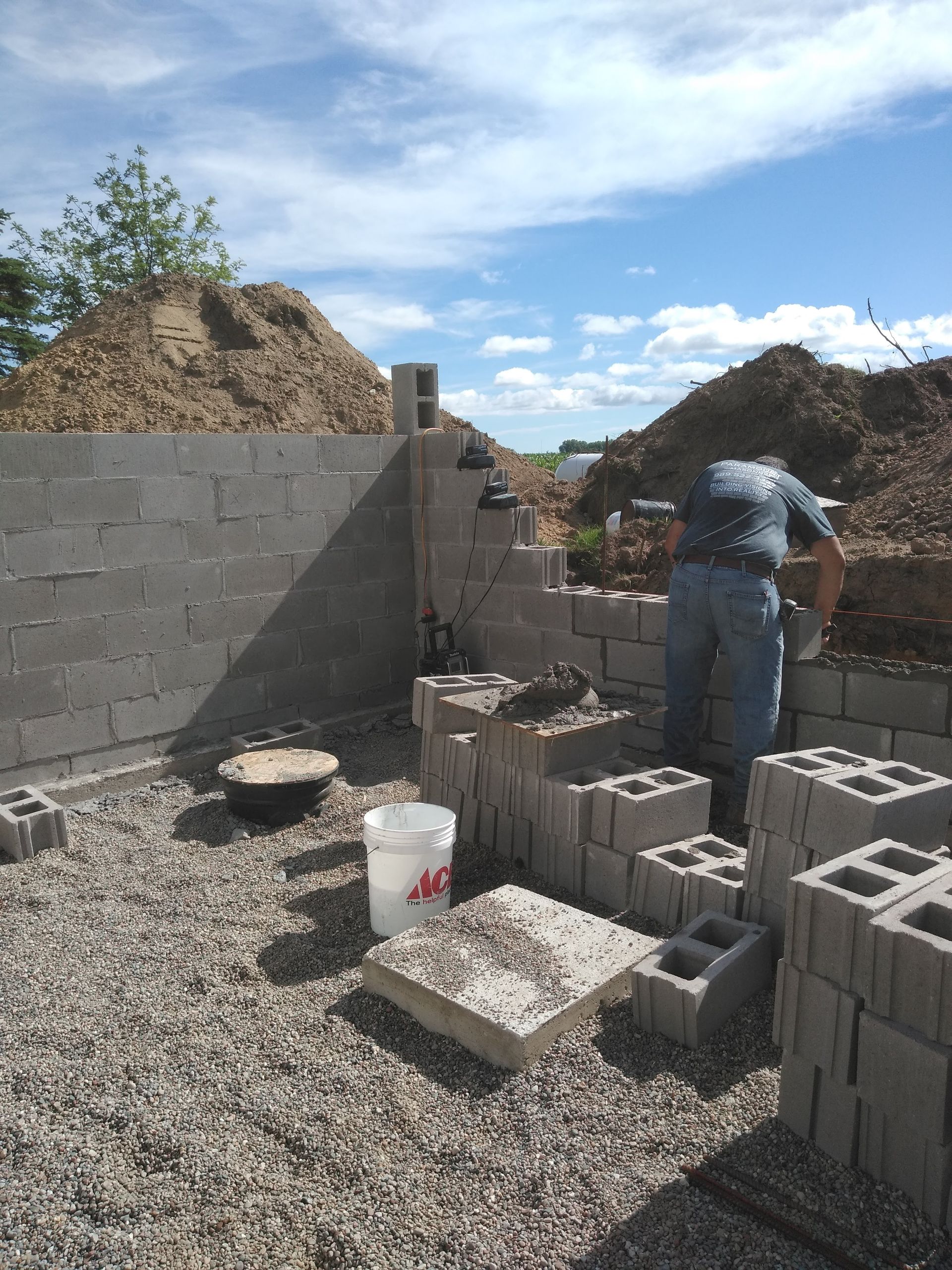 A man is working on a wall made of concrete blocks