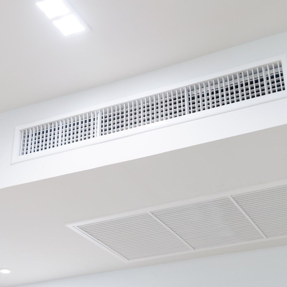 White ceiling with rectangular air vents and recessed lighting.
