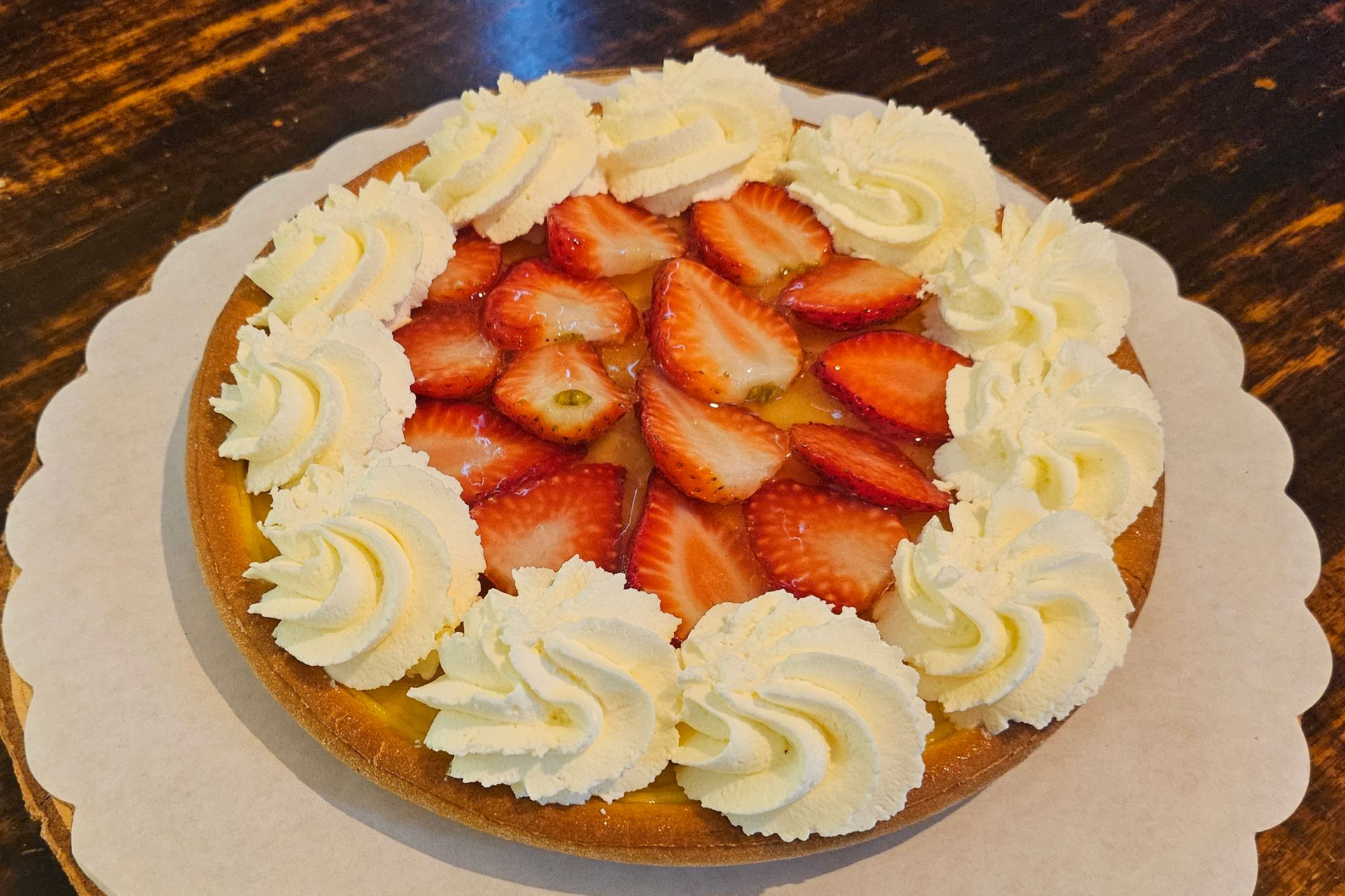 Een ronde aardbeientaart met toefjes slagroom 22cm.