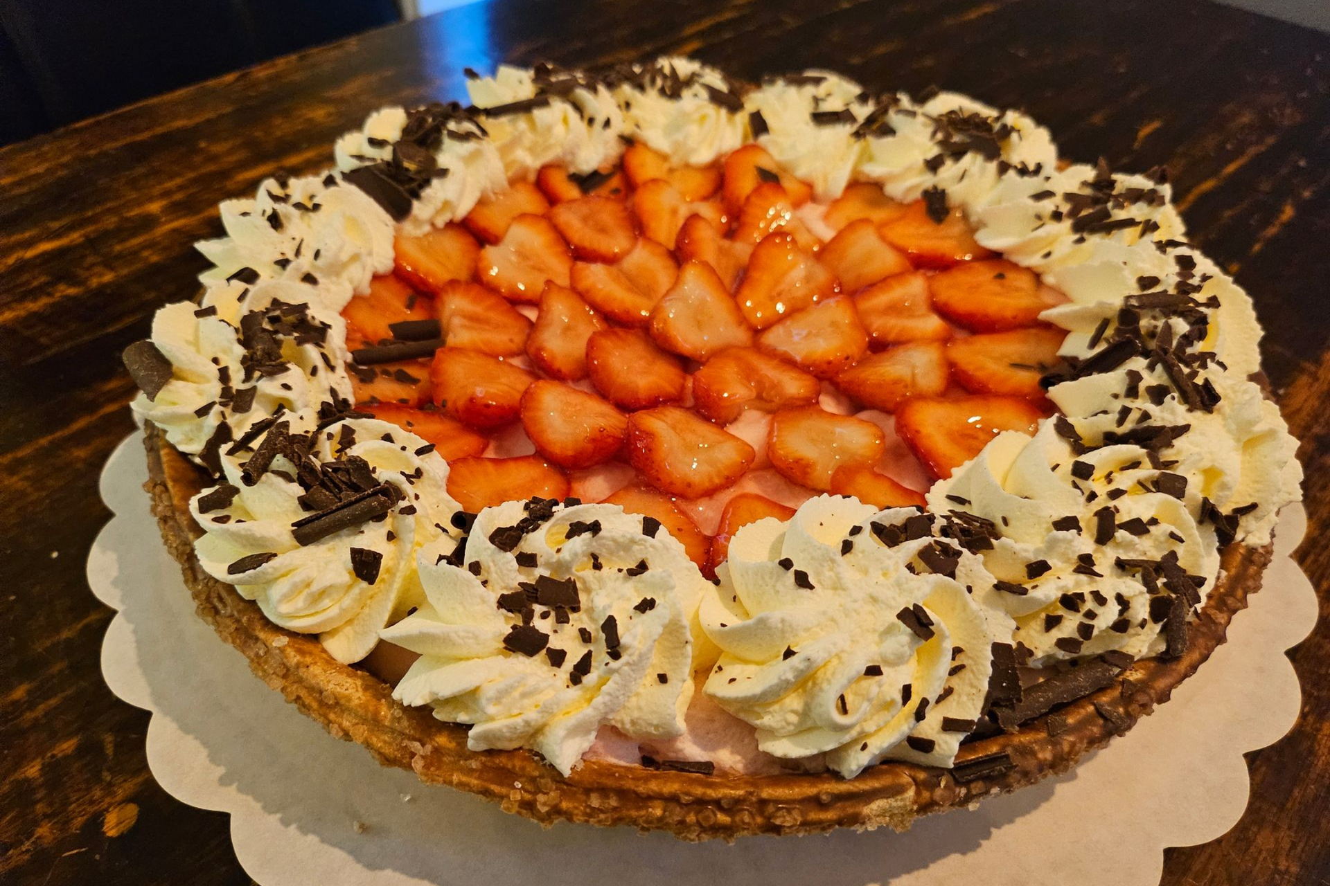 Een aardbeientaart met slagroomkrullen en chocoladeschaafsel.