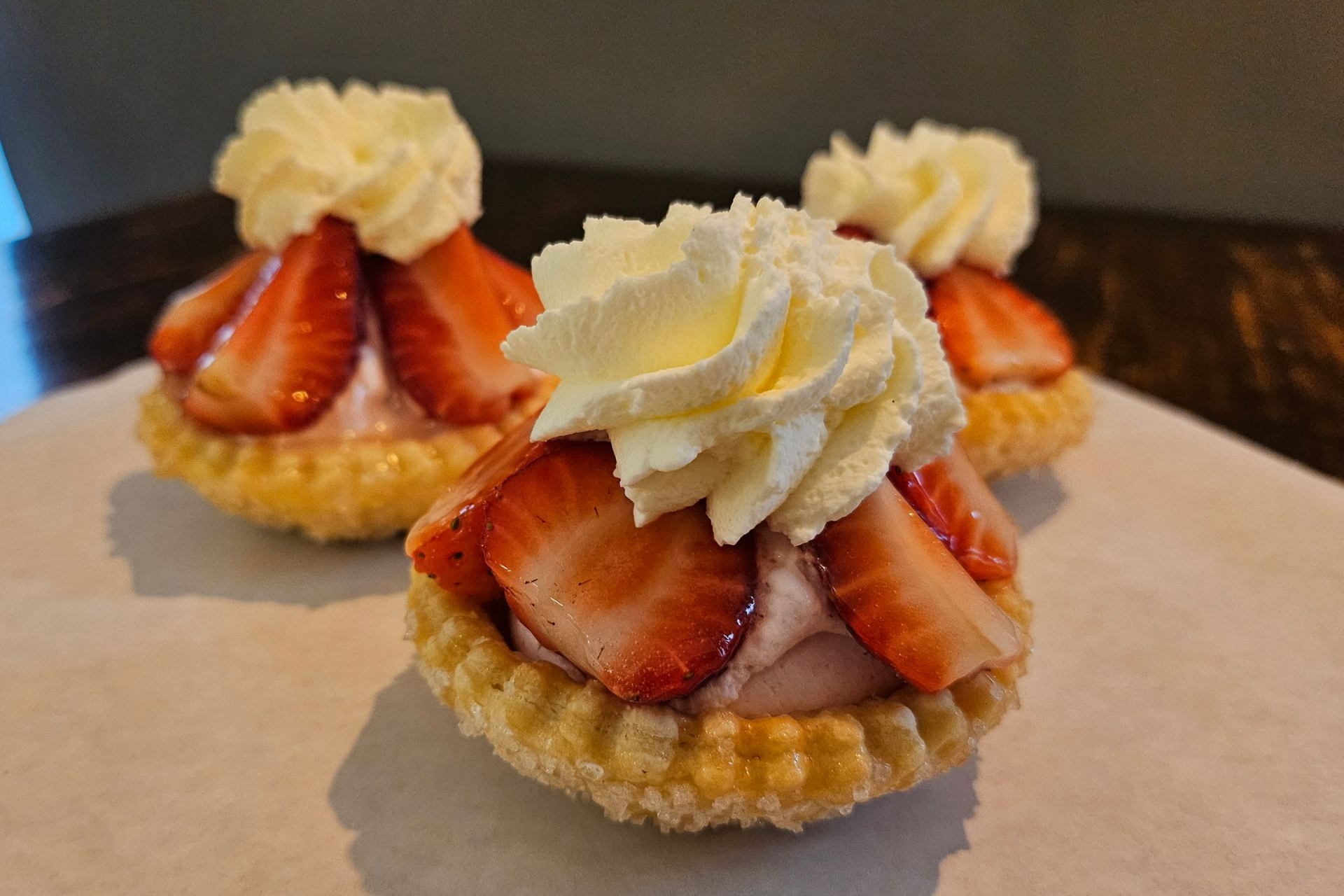 Drie aardbeientaartjes, afgetopt met slagroom.