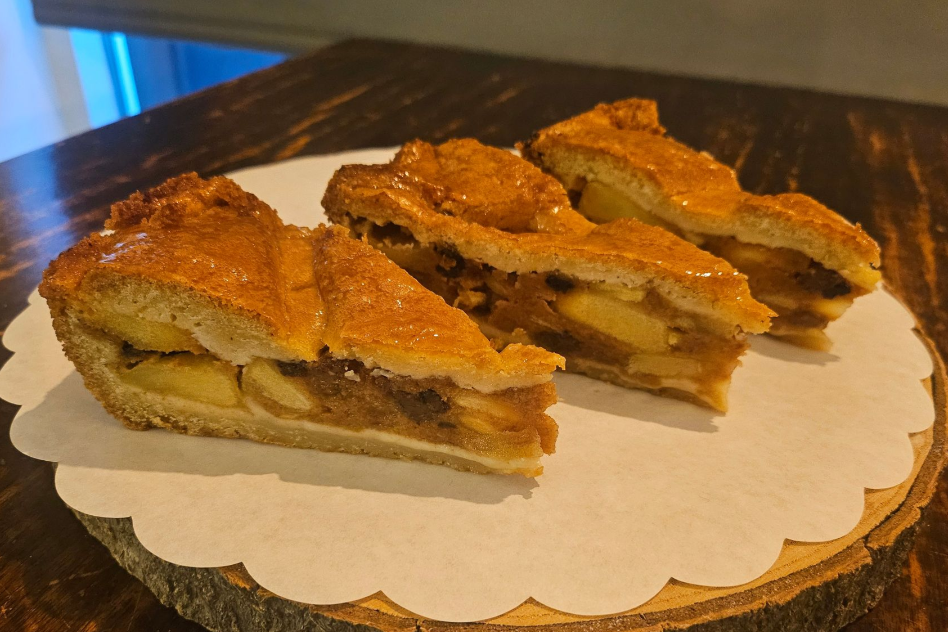 Drie plakken goudbruine appeltaart met een rastervormige korst.