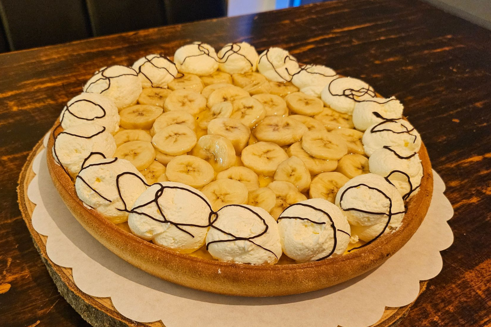 Een bananentaart, versierd met slagroomkrullen en besprenkeld met chocoladestrepen.