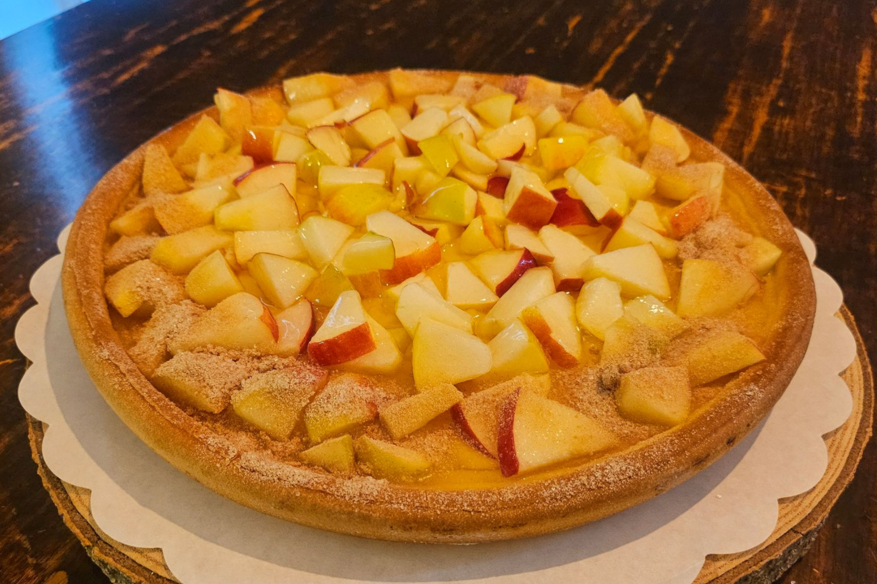 Een ronde appeltaart met stukjes appel en een goudbruine korst.