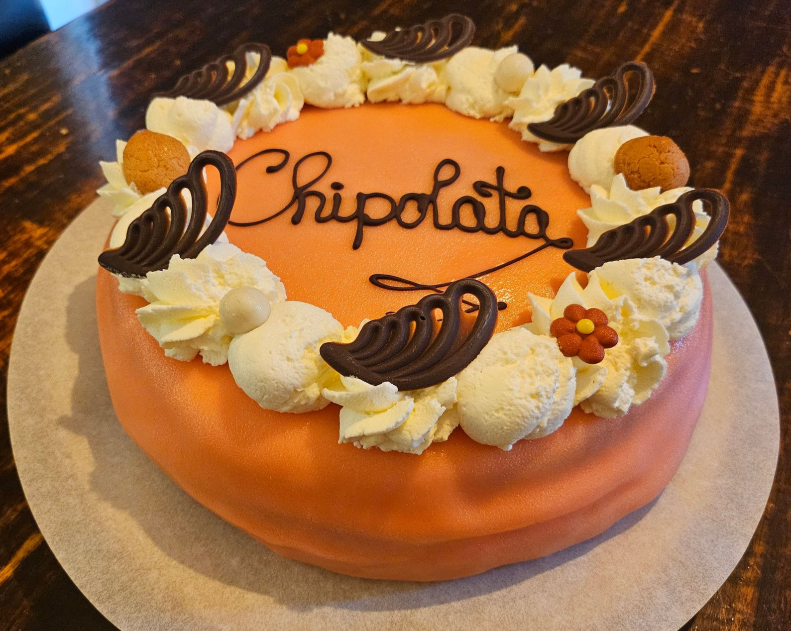 Chipolata taart met witte slagroom, cremé en chocoladekrullen, met het opschrift 