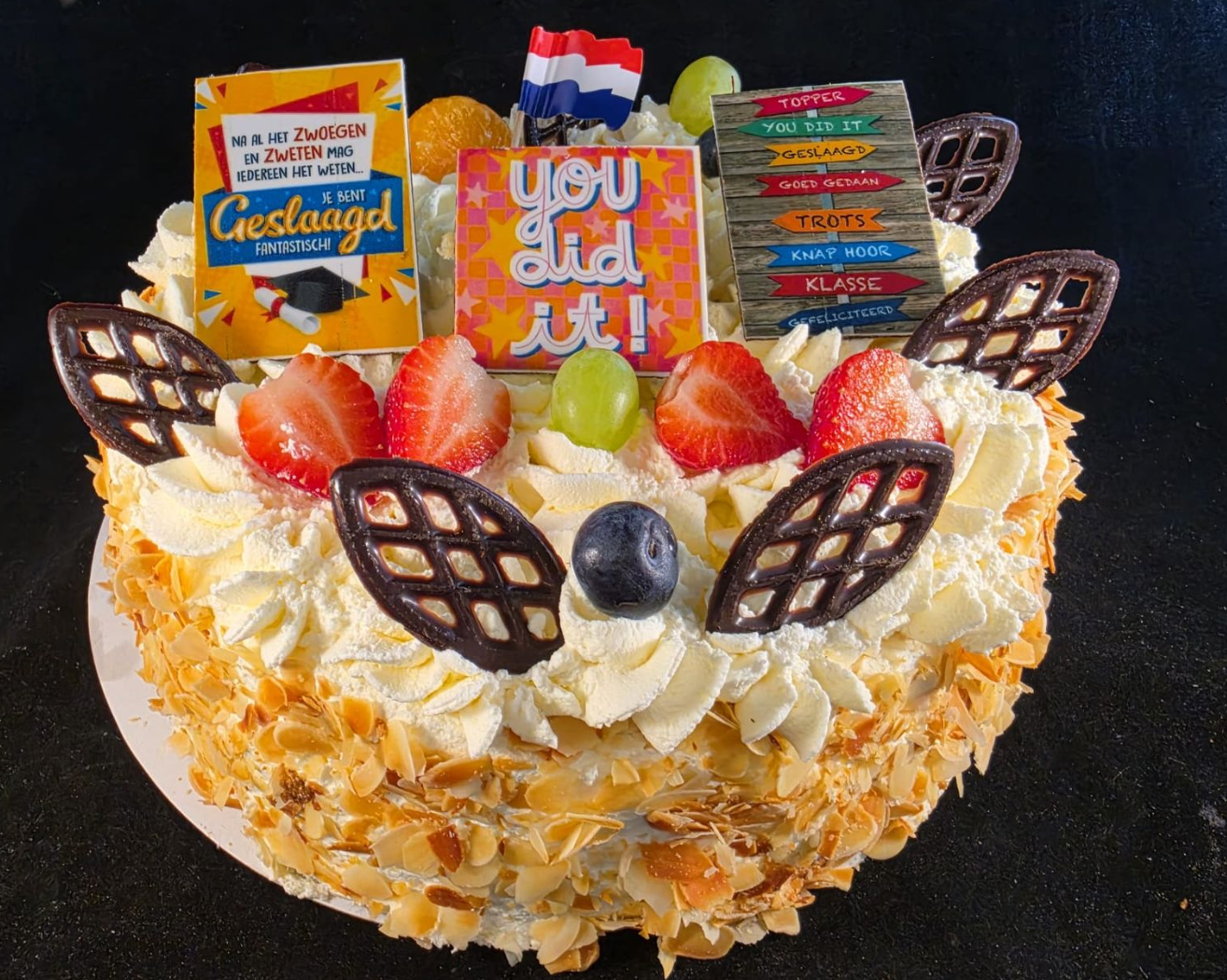 Versierde taart met slagroom, fruit, chocoladeraster en snoeptoppings.