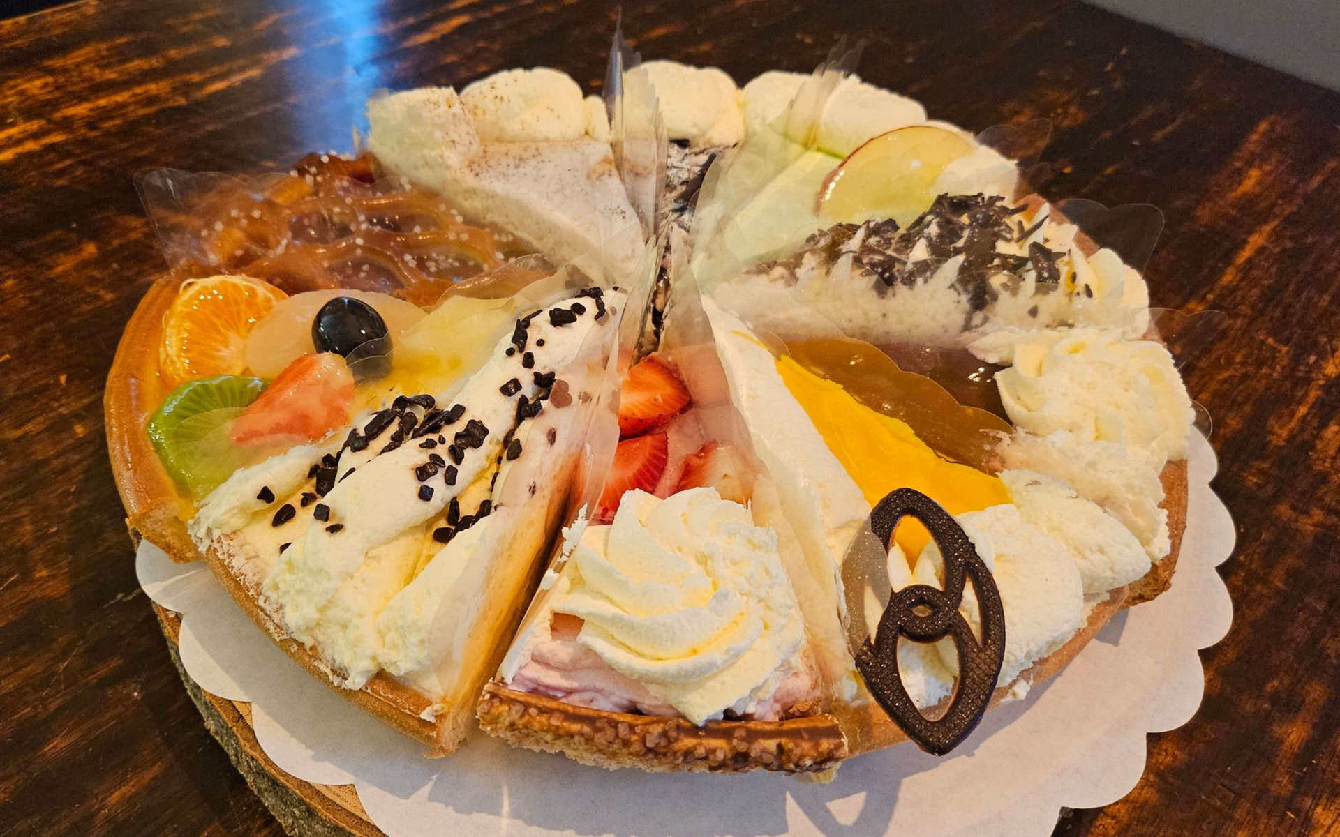 Diverse stukken taart met fruit en slagroom..