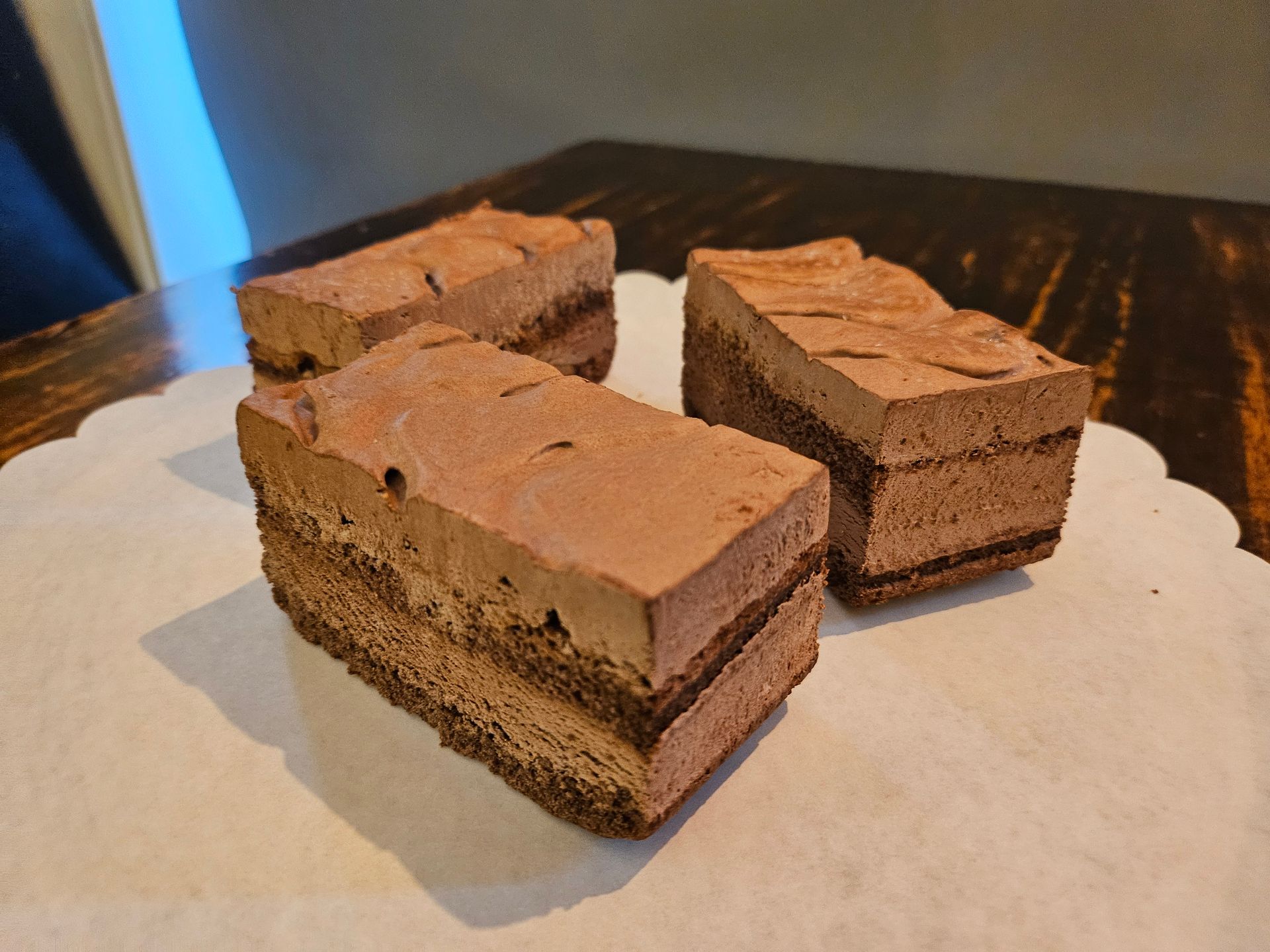 Drie rechthoekige plakken gelaagde chocolademoussetaart.