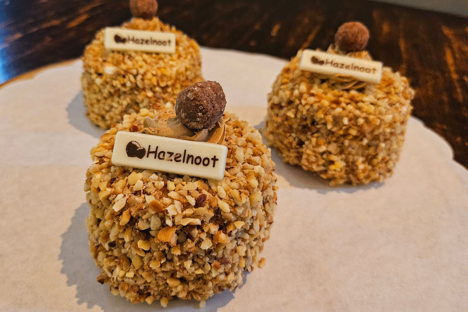 Drie hazelnootgebakjes met chocolade en een bordje van witte chocolade.