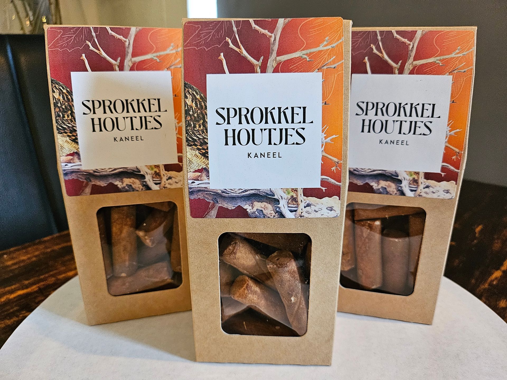 Drie dozen Sprokkel Houtjes in beige en rode verpakking.