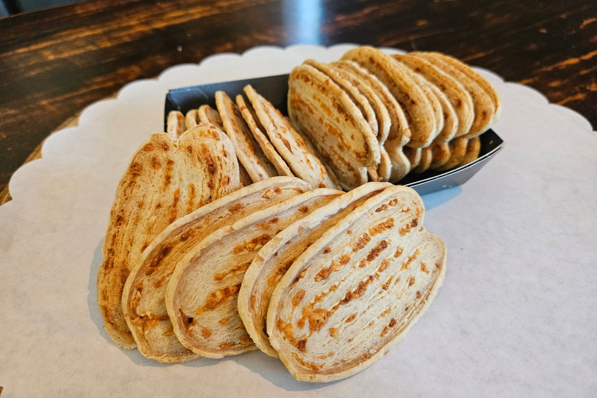 Een schaal met ovale, goudbruine vlinders met zichtbare kruiden- of specerijenspikkels.