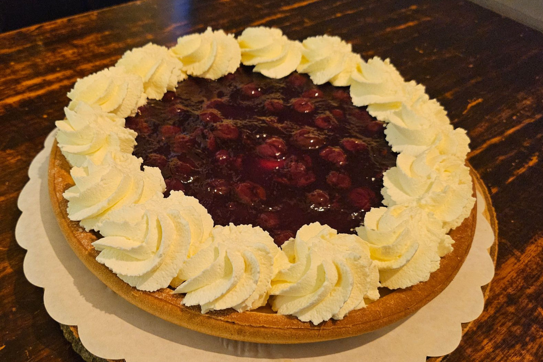 Een kersentaart met een ring van slagroom langs de rand.