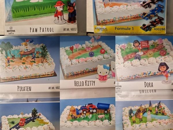 Een raster van taartdecoratiesets met verschillende personages en thema's, waaronder Paw Patrol, racen en dieren.