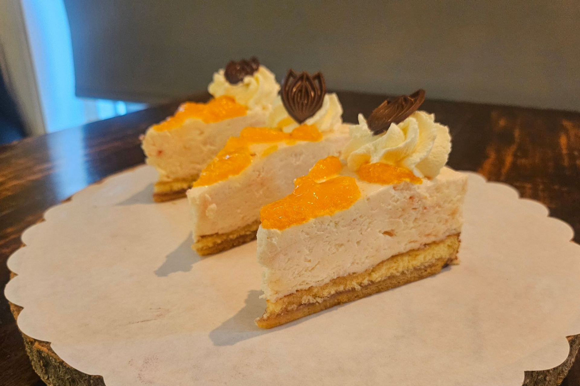 Drie plakken sinaasappelmoussetaart, gegarneerd met slagroom en chocolade.