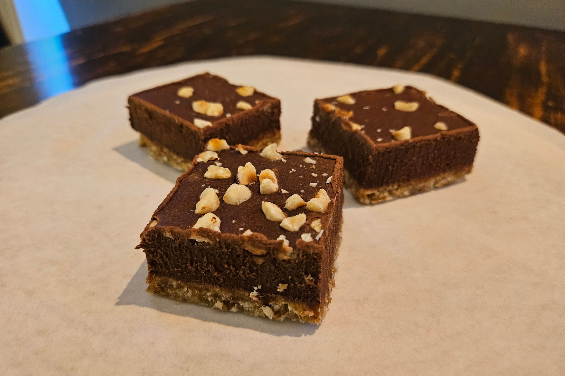 Drie vierkante repen chocoladeganache met noten als topping.