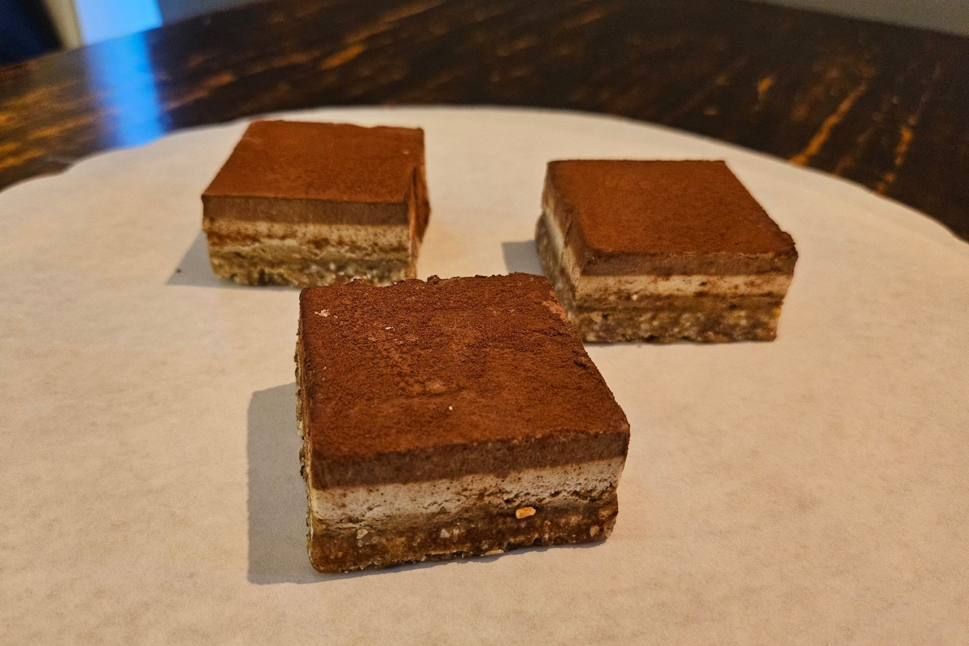 Drie vierkante, meerlaagse chocoladerepen met de smaak tiramisu. Afgetopt met cacaopoeder.