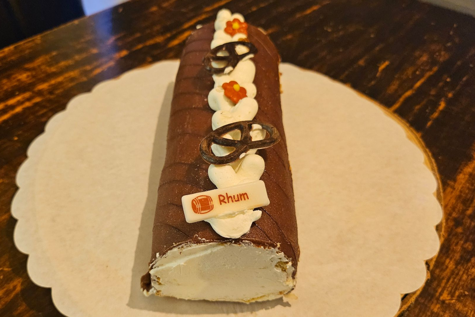 Een Zwitserse chocoladerol, versierd met slagroomkrullen, kleine oranje bloemetjes en chocoladefiguurtjes.