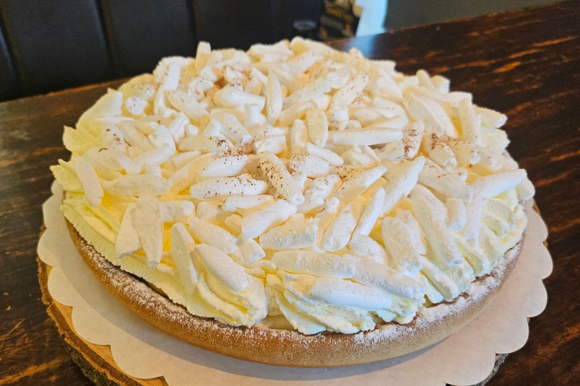 Een ronde taart, bedekt met stukjes witte schuim en een lichte bestrooiing met cacao.