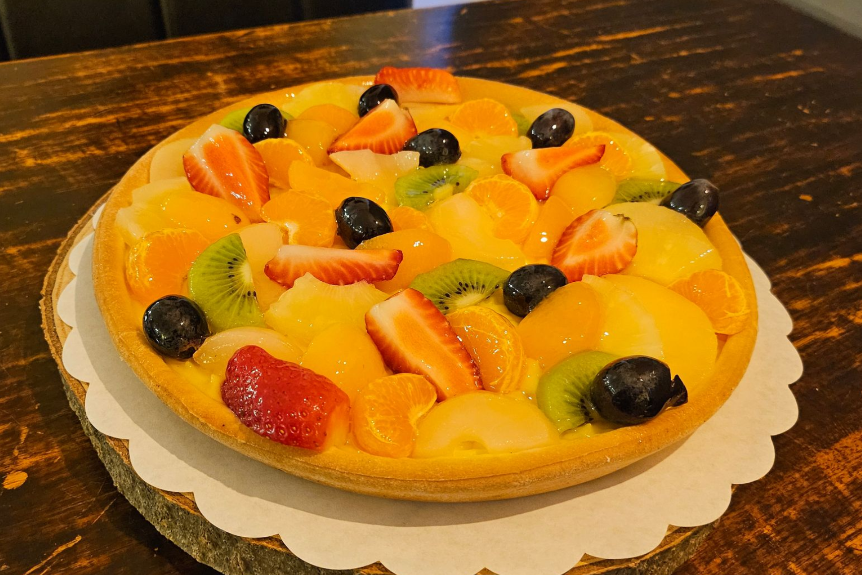 Een vruchtentaart, belegd met aardbeien, kiwi, mandarijnen en druiven.