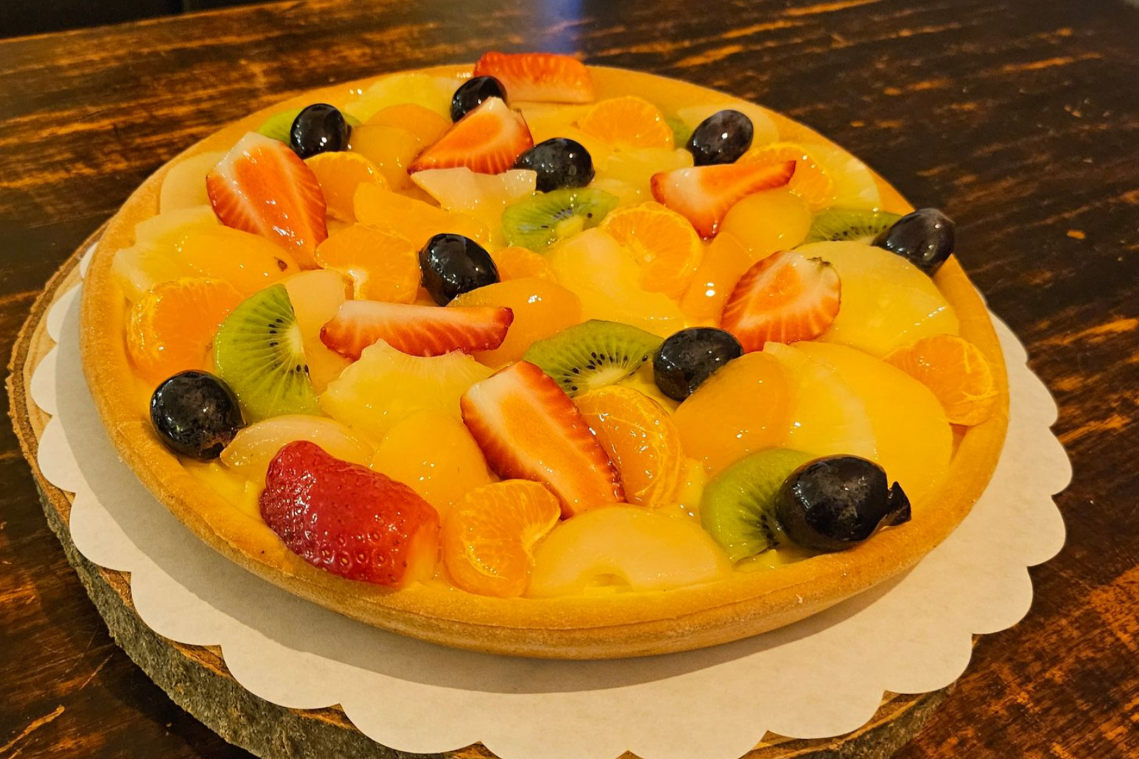 Een vruchtentaart, belegd met aardbeien, kiwi's, druiven en citrusvruchten.