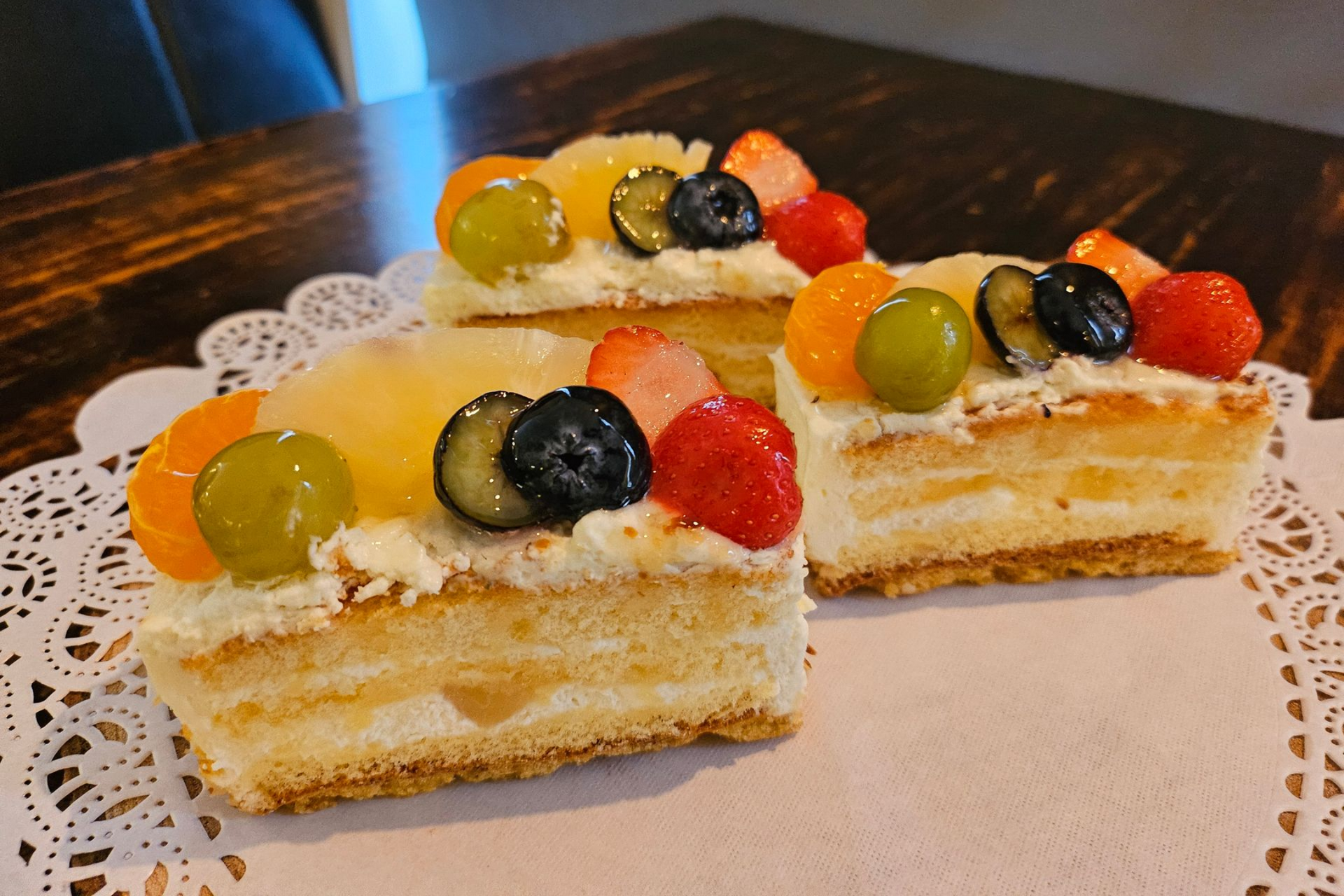 Twee plakken gelaagde cake met fruit erop.