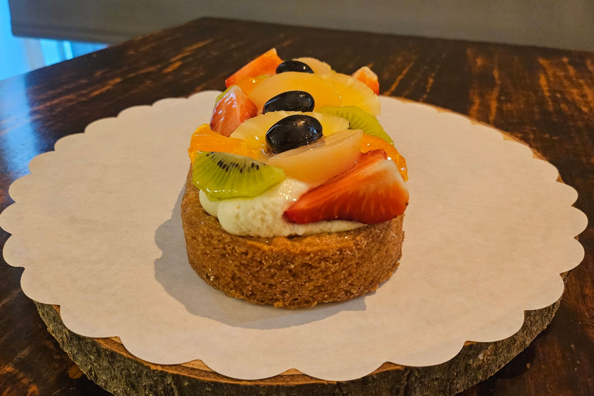 Een klein fruittaartje, belegd met aardbeien, kiwi, perzikschijfjes en druiven.