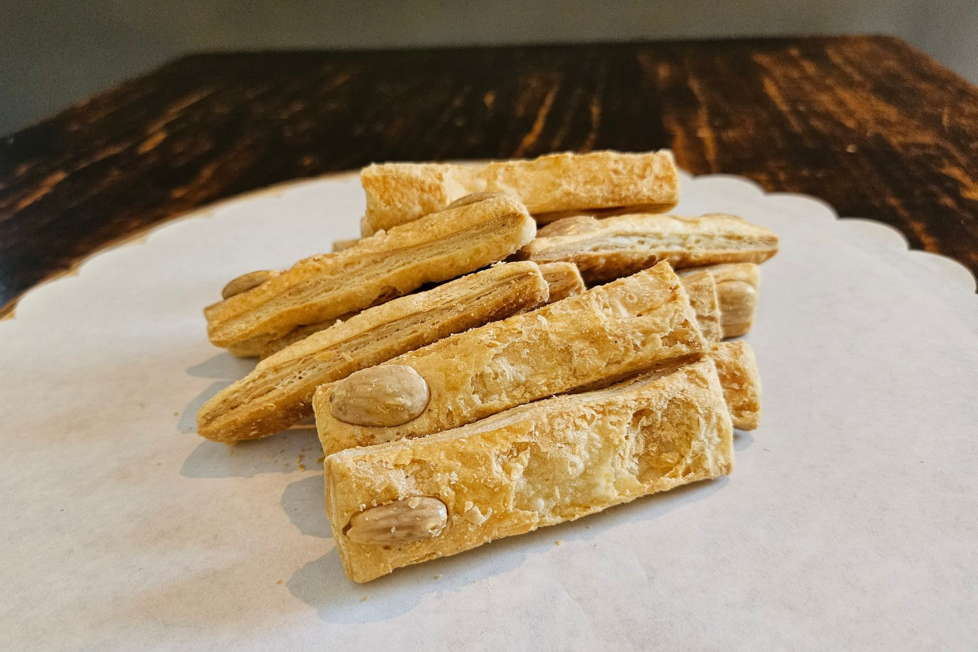 Een stapel goudbruine amandelbladerdeegstokjes.