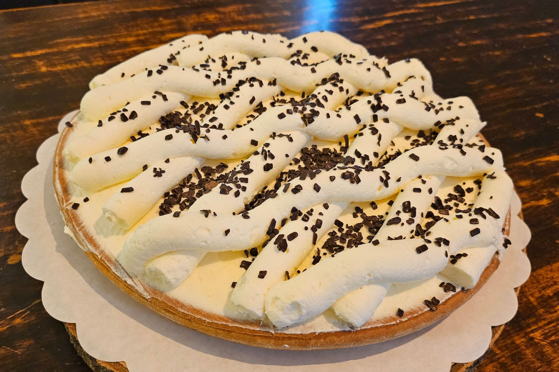 Een ronde taart, versierd met toefjes slagroom en chocoladeschaafsel.