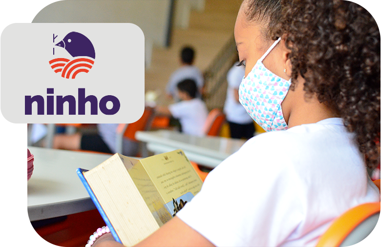 Una niña leyendo en la escuela, usando mascarilla. A la derecha, el logo blanco, azul y rojo del Proyecto Ninho.