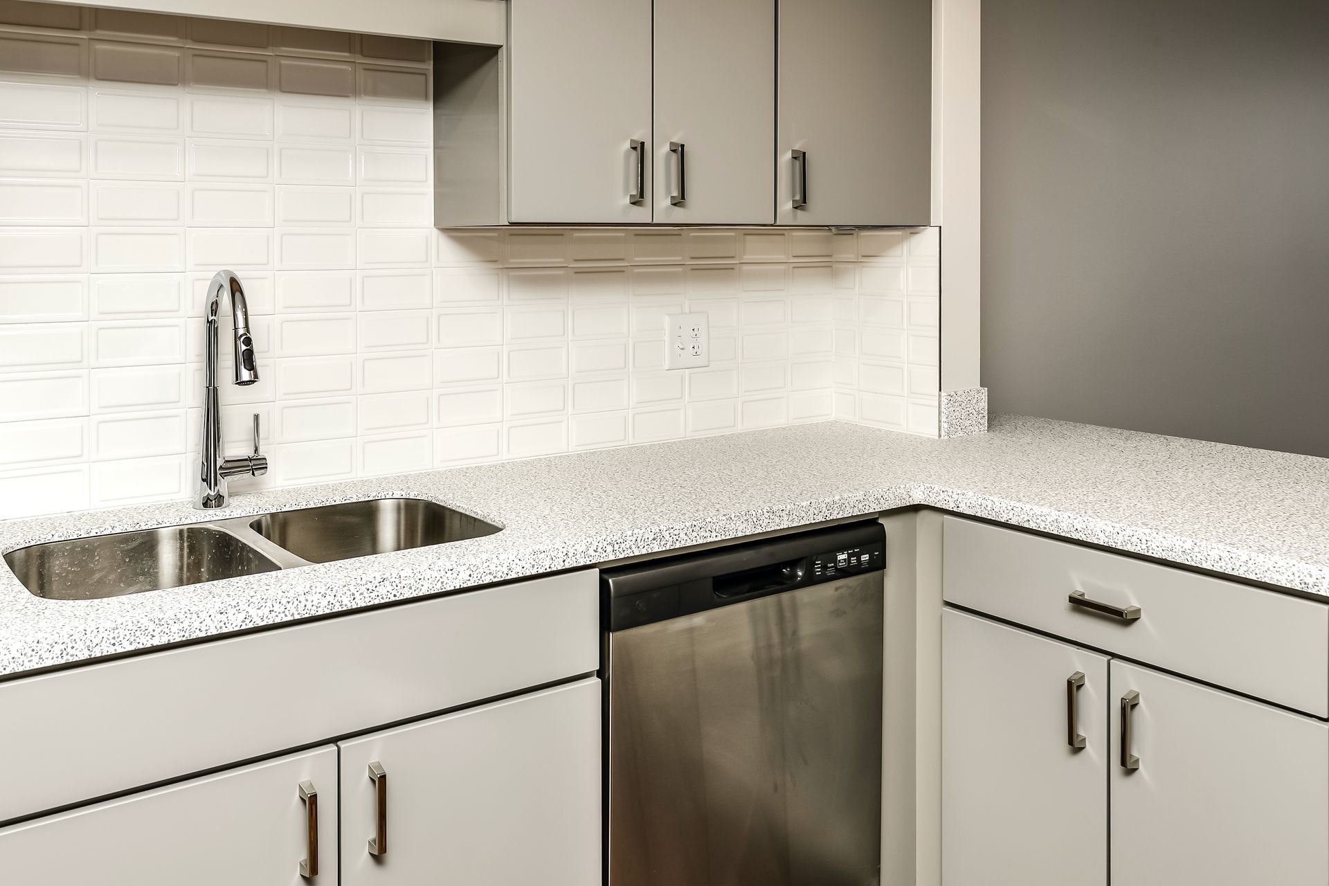 Modern white kitchen corner with sink, stainless dishwasher, and white cabinets