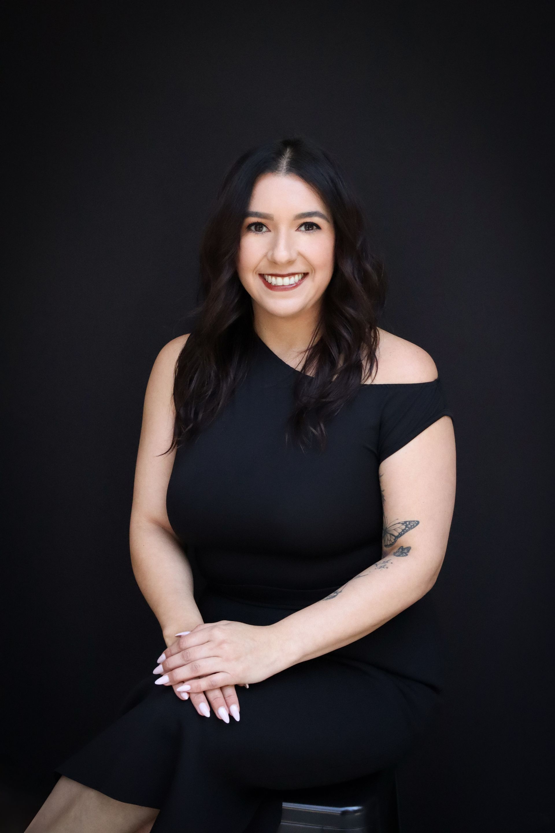 A woman is sitting at a desk with a laptop and a vase of flowers.