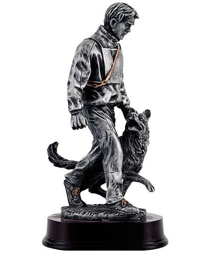 Zwart-wit beeldje van een man die met een hond loopt, op een sokkel.
