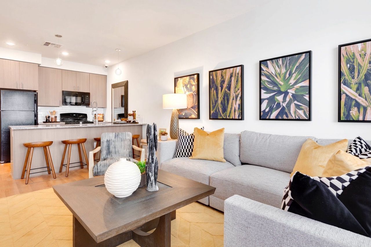 Open-concept living area with kitchen island, bar stools, and a gray sectional sofa.