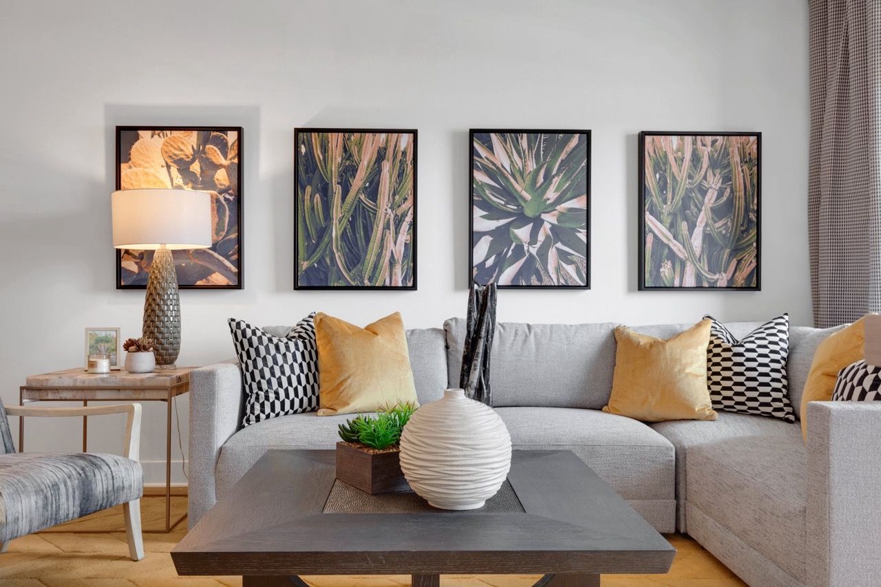 Living room in a modern apartment with a gray sectional, decorative pillows, and wall art.