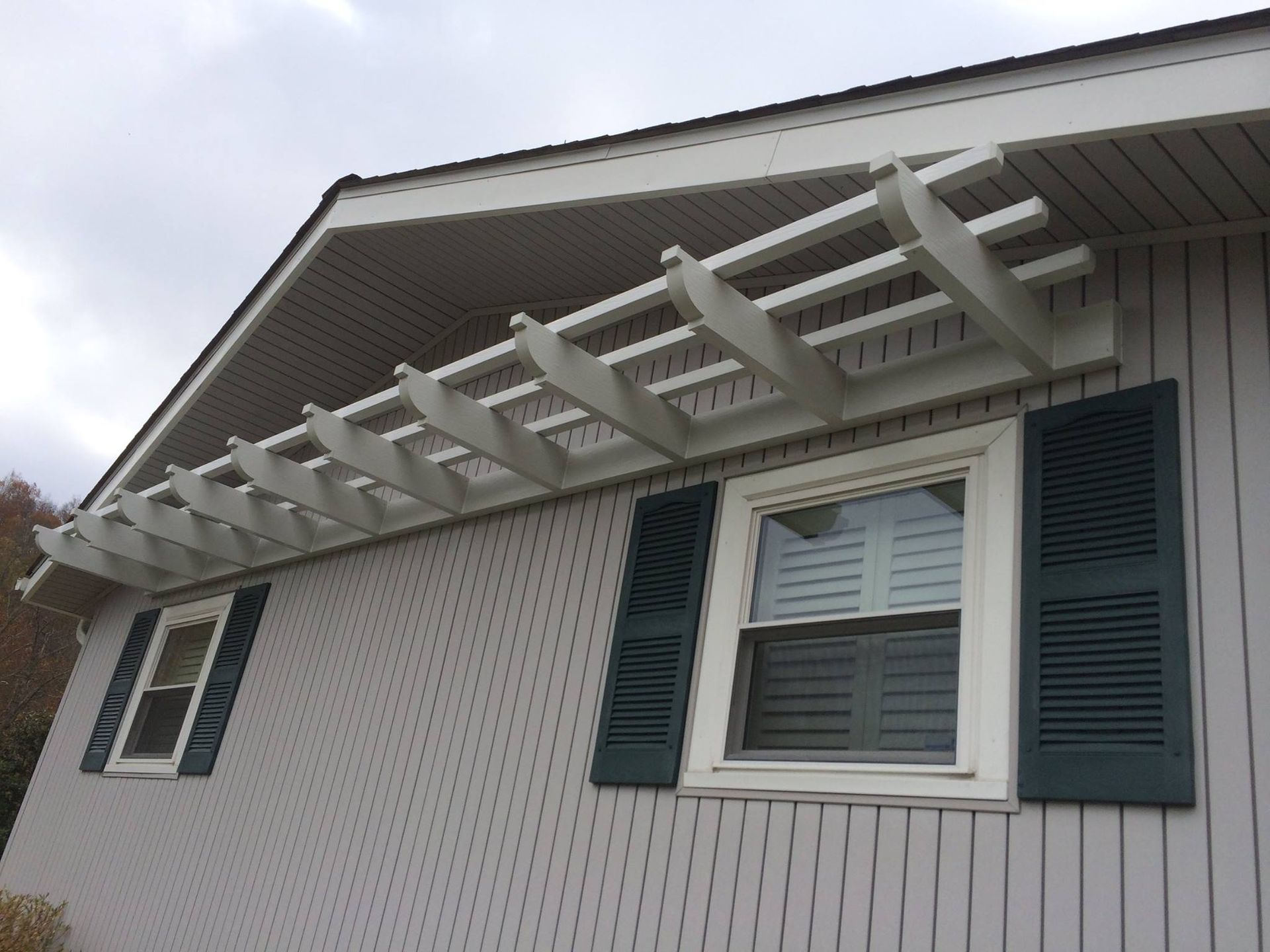 A white house with blue shutters and a white pergola
