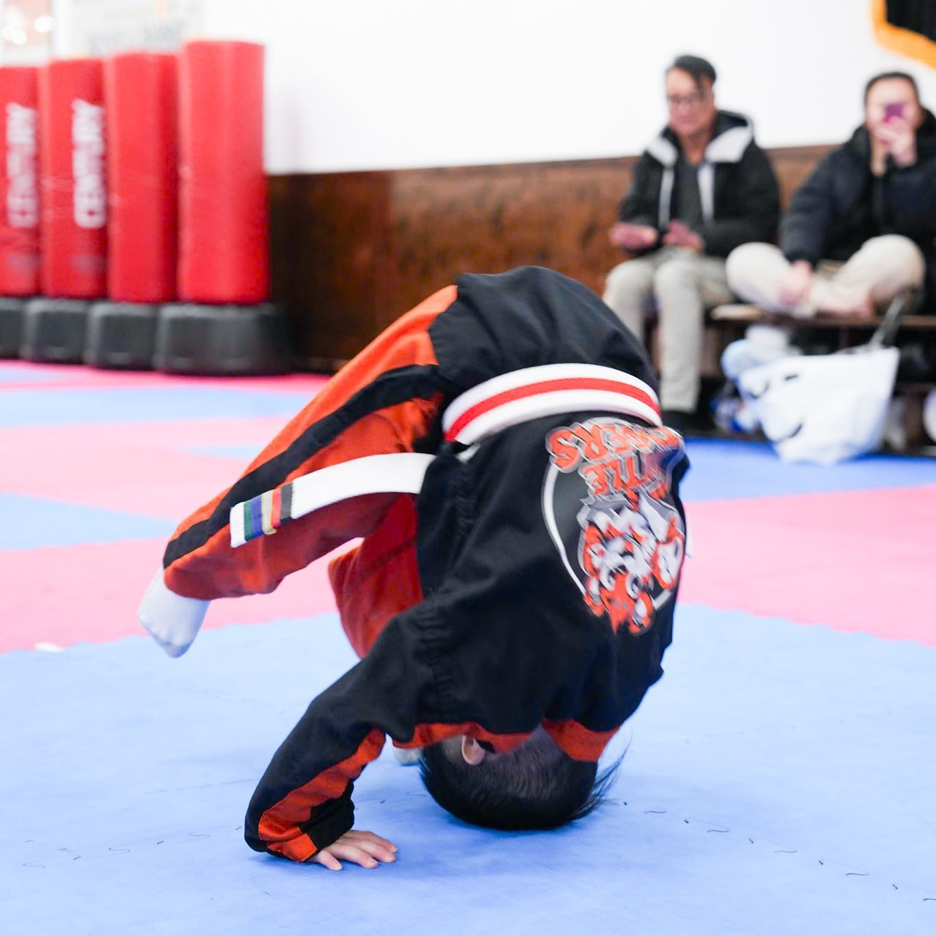 A young boy is doing a handstand on a blue mat