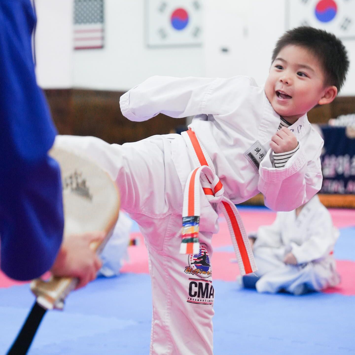 A young boy is practicing martial arts with a medal that says cma