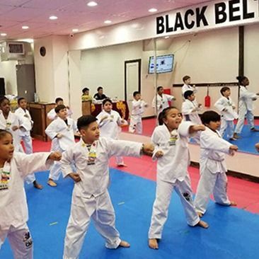 A group of children are practicing martial arts under a sign that says black belt