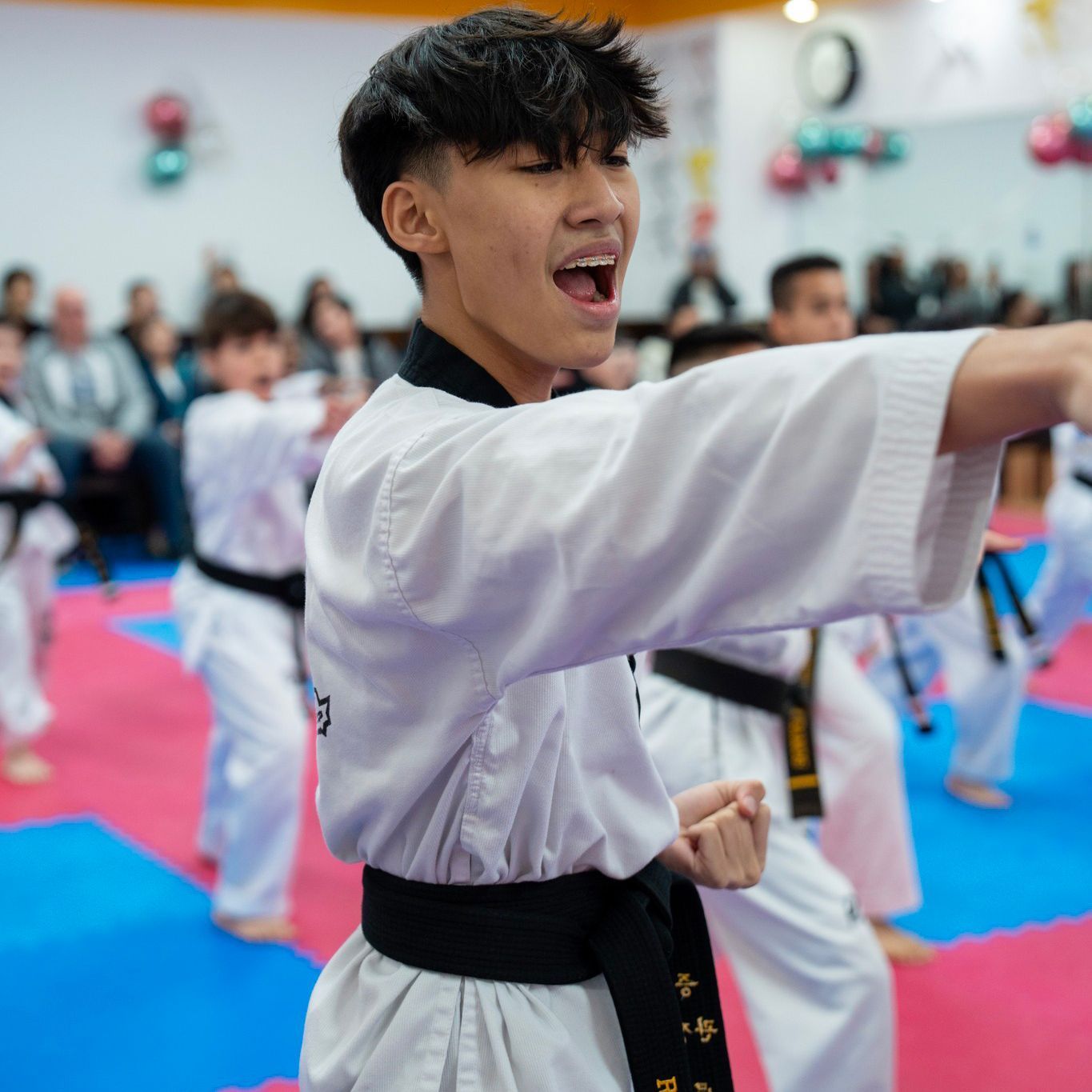 A group of kids are practicing martial arts in a gym