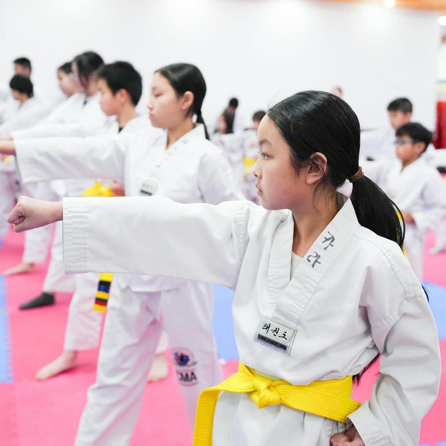 A girl in a white karate uniform has a yellow belt around her waist