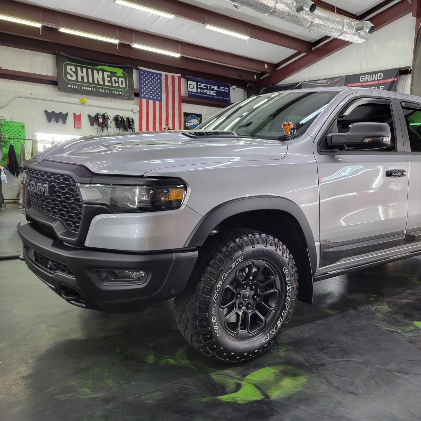 Silver Ram truck parked inside a garage, next to a US flag.