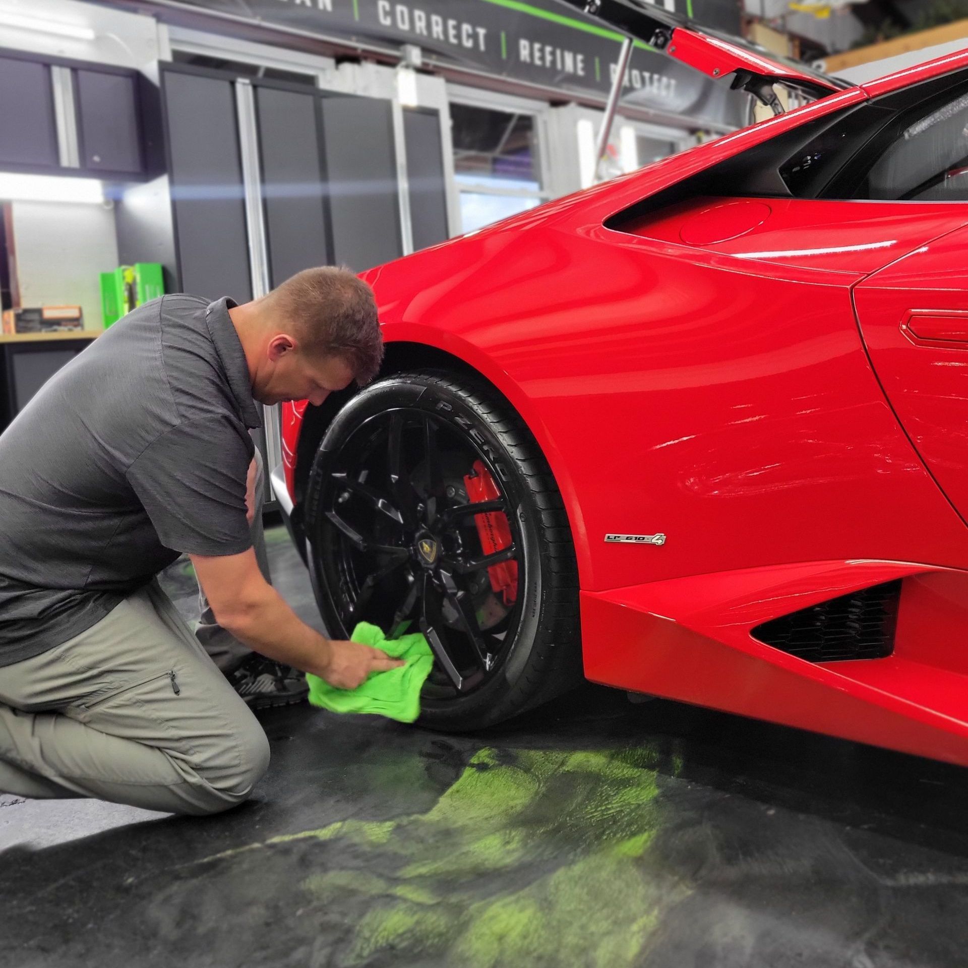 A man is kneeling down next to a red sports car