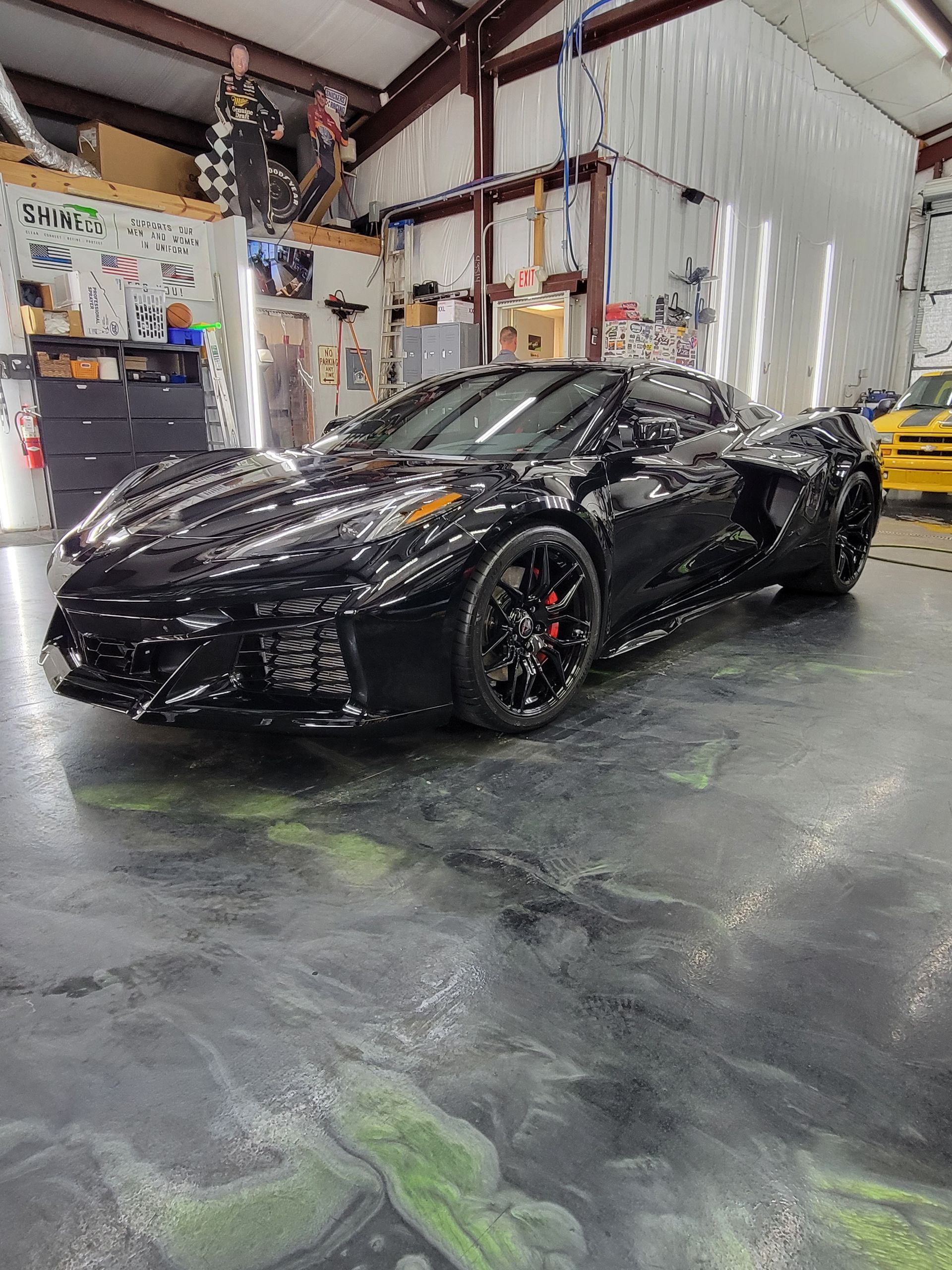 White BMW sedan in a garage, black wheels, tinted windows.