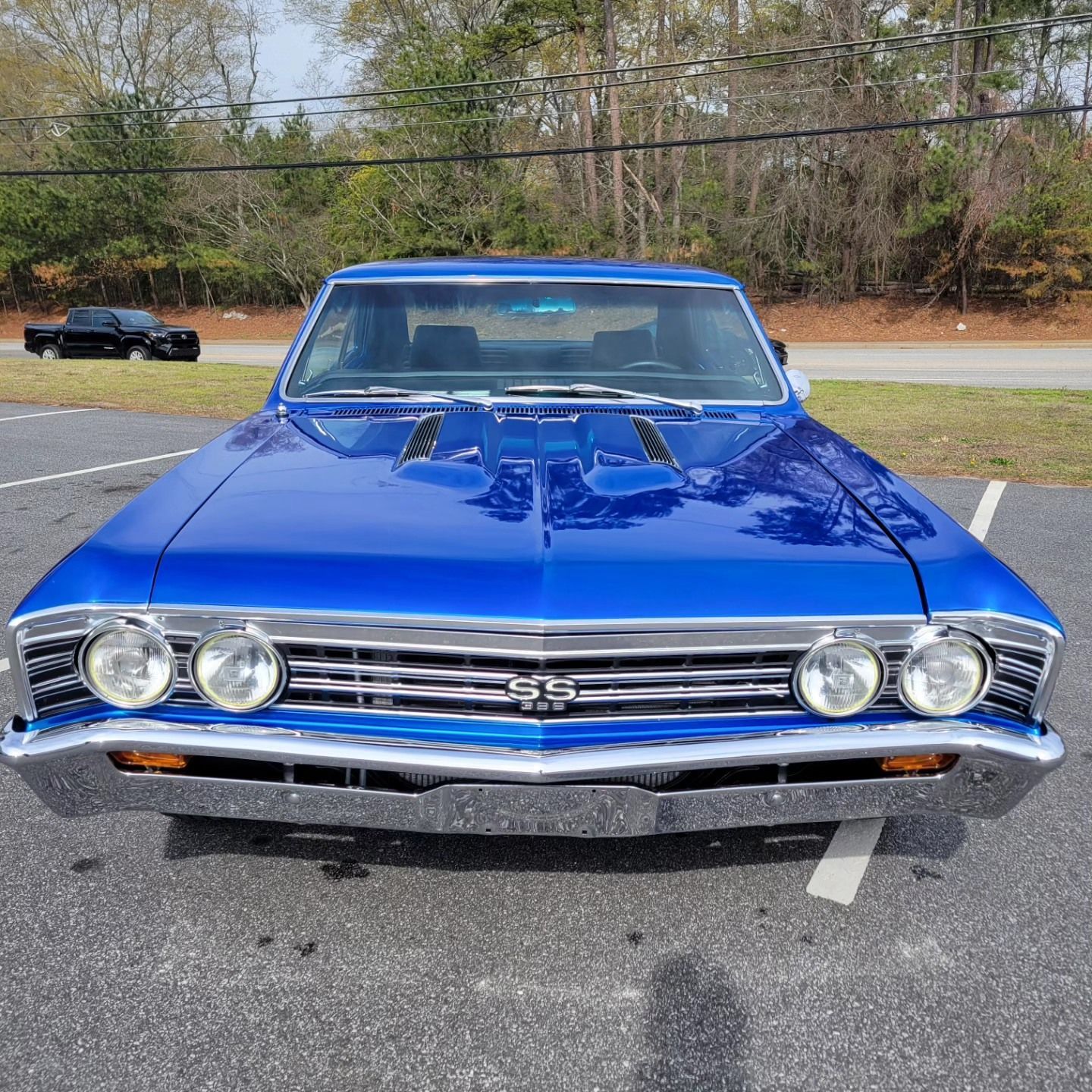 A vibrant blue Chevrolet Chevelle SS parked in an outdoor lot on a sunny day, facing forward.
