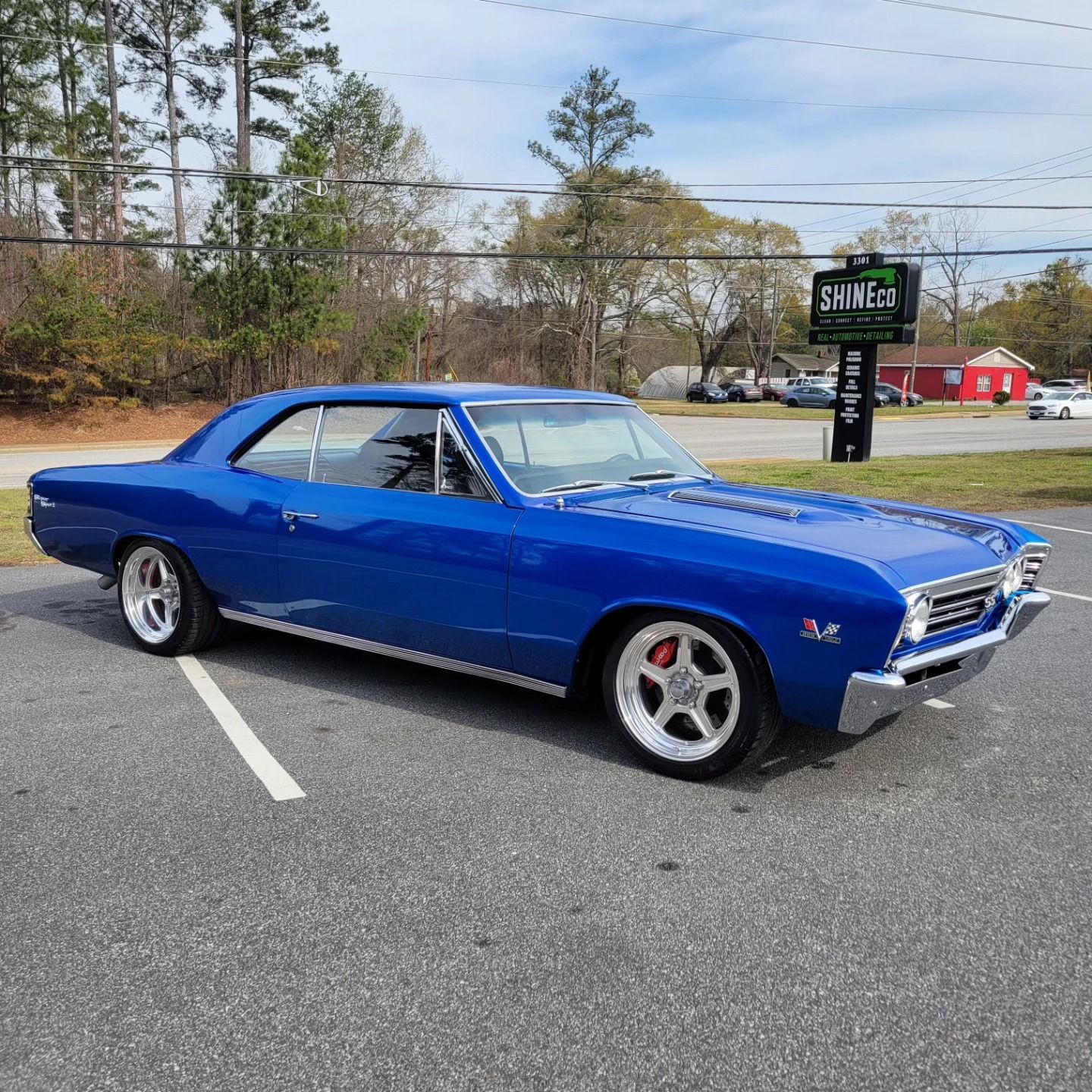 A bright blue classic Chevrolet Chevelle parked in an asphalt lot on a sunny day.