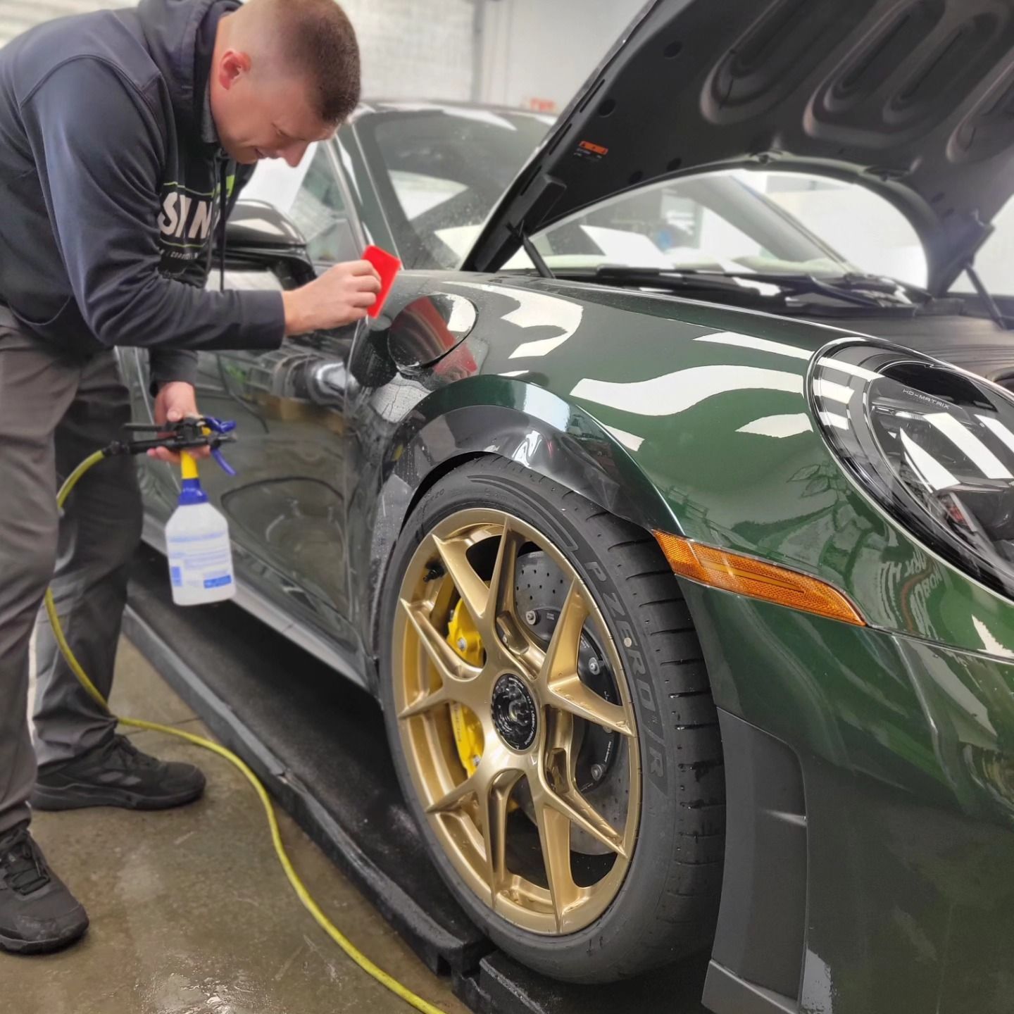 Paint protection film installation on a green sports car with technician applying to front fender