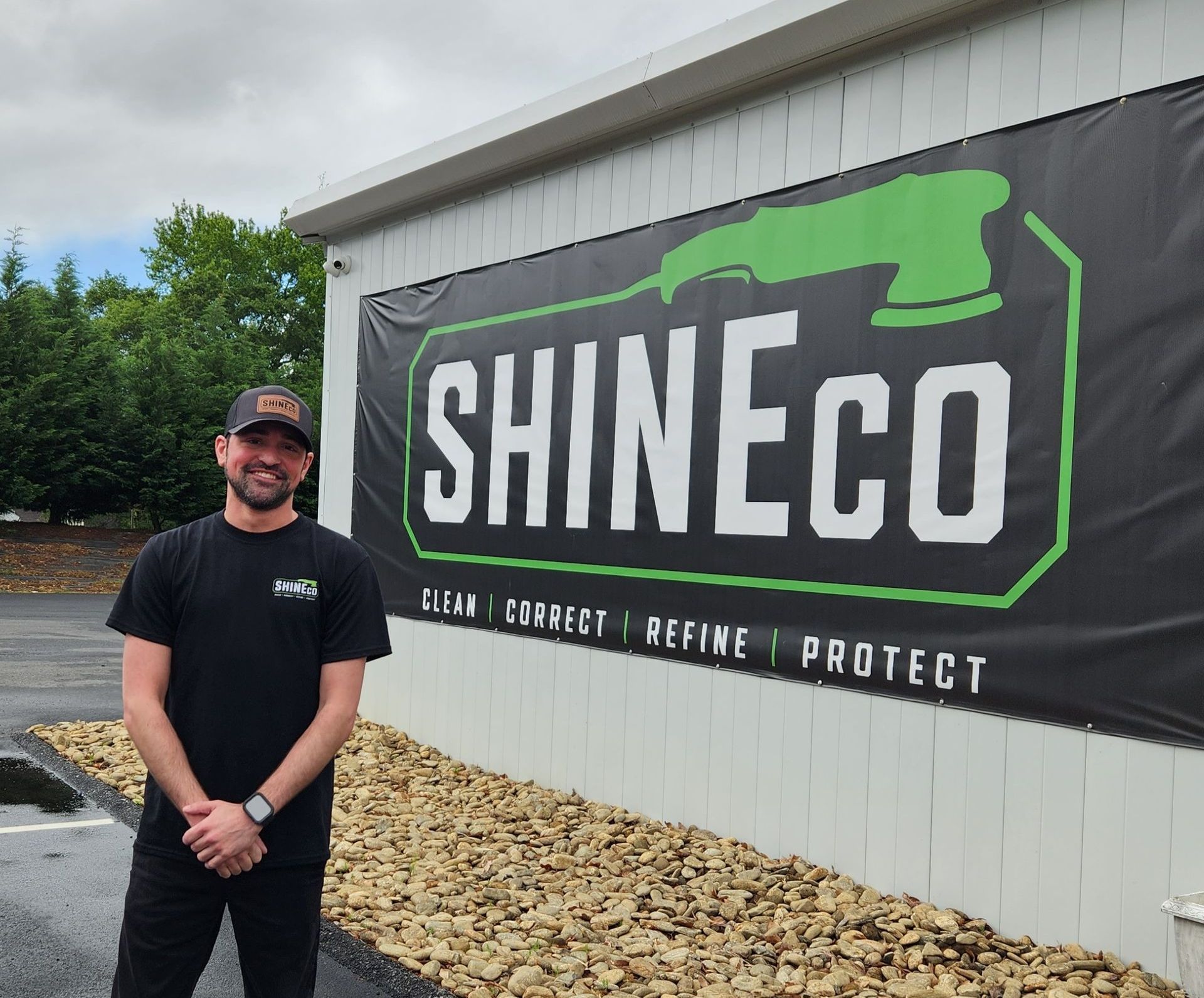 A man is standing in front of a shineco sign