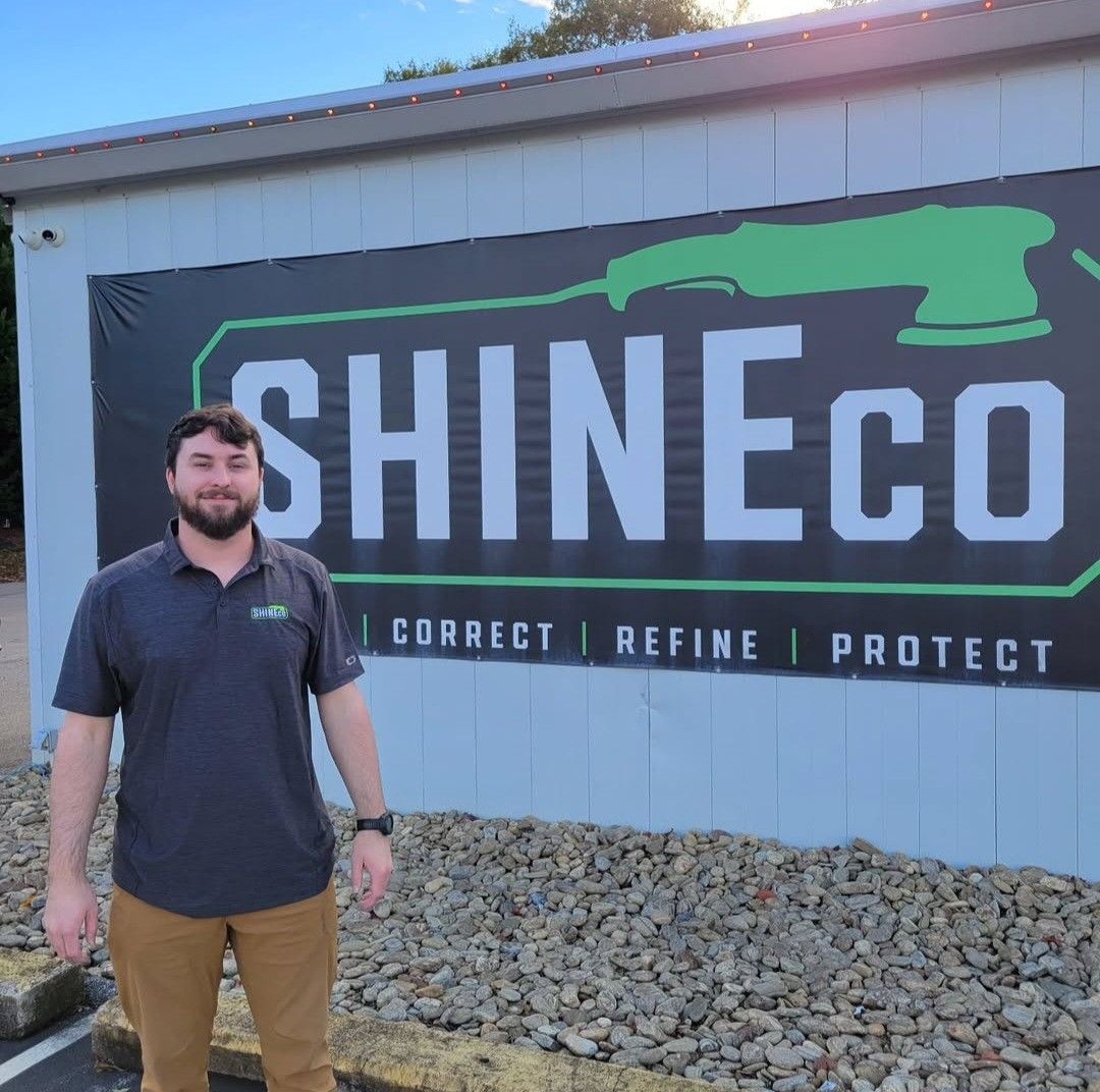 Man standing in front of ShineCo sign, building exterior. Green and white logo.